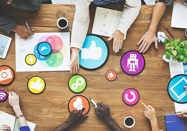 People collaborating around a table with colorful app icons digitally overlaid.